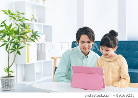 A girl and a man looking at a tablet in the living room A girl and a man looking at a tablet in the living room 99169235
