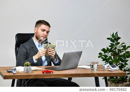 young bearded businessman working on laptop and holding money young bearded businessman working on laptop and holding money 99170982