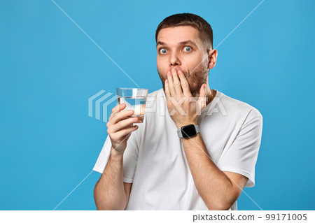 surprised handsome man with drinking glass of water surprised handsome man with drinking glass of water 99171005