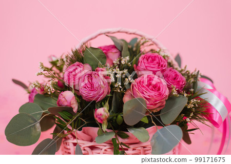 Bouquet of pink roses in a wicker basket on a pink table background. Birthday, Wedding, Mother's Day, Valentine's Day, Women's Day. Front view Bouquet of pink roses in a wicker basket on a pink table background. Birthday, Wedding, Mother's Day, Valentine's Day, Women's Day. Front view 99171675