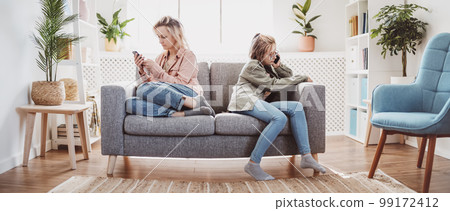 Quarreled mother and daughter sitting on the sofa back to back. 99172412