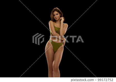 Beauty. Portrait of young attractive woman posing in olive color lingerie isolated over black background. Concept of show, body and skin care, health, plastic surgery, cosmetics, ad 99172752