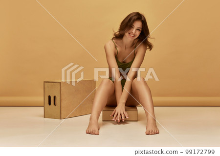 Portrait of young slim beautiful girl wearing green color underwear posing over brown background. Concept of beauty, body and skin care, healthy eating Portrait of young slim beautiful girl wearing green color underwear posing over brown background. Concept of beauty, body and skin care, healthy eating 99172799