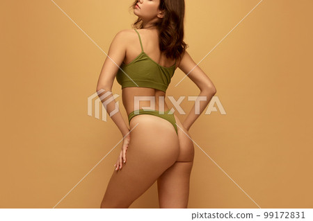 Adorable beautiful caucasian woman with slim fit figure in olive color inner wear posing on yellow studio background. Concept of female body, health, sport, spa, ad 99172831