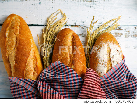 Assortment of fresh baked bread, rye and wrapped clothon white wooden background 99173402