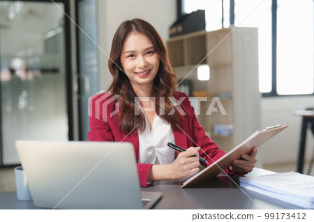 Beautiful asian business woman working on a laptop at office. Financial analysis and tax concept Beautiful asian business woman working on a laptop at office. Financial analysis and tax concept 99173412