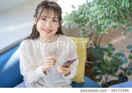 A young lady manipulating a smartphone on the sofa 99173596