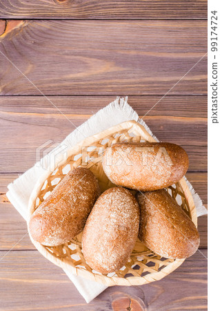Fresh rye buns in a basket on a wooden table. Top view. Copy space 99174724