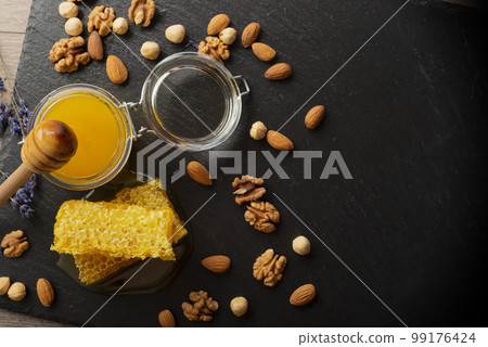 Honeycomb on slate tray with honey and nuts on kitchen table Honeycomb on slate tray with honey and nuts on kitchen table 99176424
