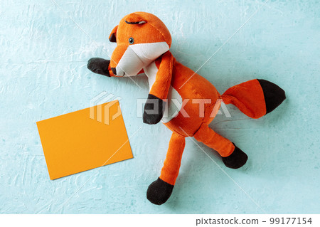Mockup with an orange greeting card and a toy fox. A mock-up 99177154
