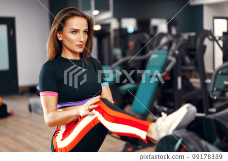 Beautiful girl fitness trainer stretching her body after workout Beautiful girl fitness trainer stretching her body after workout 99178389