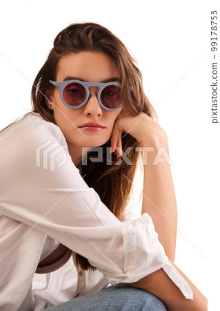 Portrait of young beautiful woman in stylish clothes and trendy sunglasses posing against white studio background. Concept of beauty and fashion 99178753