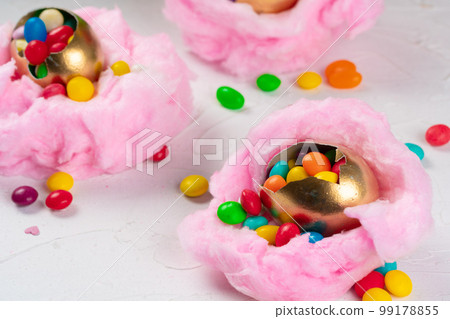 Egg shell with colorful candies inside in a decorative Easter nest Egg shell with colorful candies inside in a decorative Easter nest 99178855