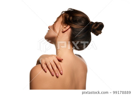 Side view image. Healthy back, massage. One beautiful brunette girl posing against white studio background. Concept of natural beauty Side view image. Healthy back, massage. One beautiful brunette girl posing against white studio background. Concept of natural beauty 99178889