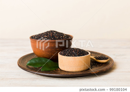 quinoa seeds in bowl and spoon on colored background. Healthy kinwa in small bowl. Healthy superfood quinoa seeds in bowl and spoon on colored background. Healthy kinwa in small bowl. Healthy superfood 99180104