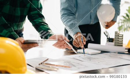 Creative architect projecting on the big drawings in the dark loft office or cafe in sun light. 99180133