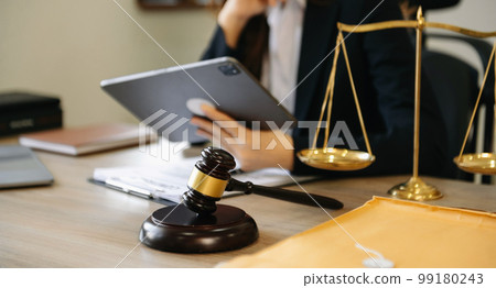 Male lawyer in the office with brass scale and using tablet and laptop on wooden table. justice and law concept 99180243