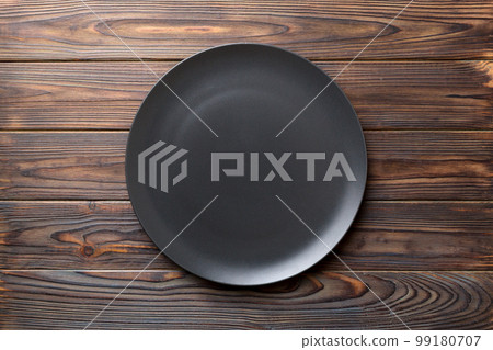 Top view of black plate on wooden background. Empty space for your design Top view of black plate on wooden background. Empty space for your design 99180707
