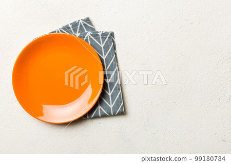 Top view on colored background empty round red plate on tablecloth for food. Empty dish on napkin with space for your design Top view on colored background empty round red plate on tablecloth for food. Empty dish on napkin with space for your design 99180784