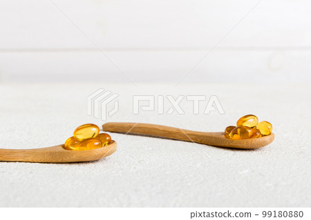 Vitamin omega capsules in a spoon on a colored background. Pills served as a healthy meal. Red soft gel vitamin supplement capsules on spoon Vitamin omega capsules in a spoon on a colored background. Pills served as a healthy meal. Red soft gel vitamin supplement capsules on spoon 99180880