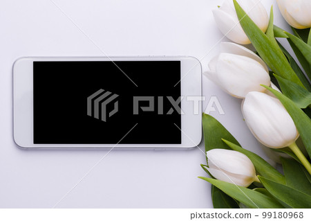 Phone with blank screen and a bouquet of white tulips. Smartphone mock up. Digital online spring greeting card. 99180968