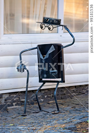 Decorative urn on the street in the form of a man with glasses and a hat. 99181536