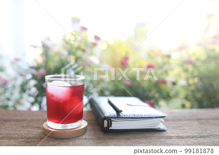 Roselle Herbal drink and notebook and daisy flower on wooden table outdoor Roselle Herbal drink and notebook and daisy flower on wooden table outdoor 99181878