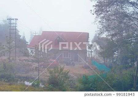 A mountain cottage in a foggy morning. Mist hill and forest in December winter landscape. A mountain cottage in a foggy morning. Mist hill and forest in December winter landscape. 99181943