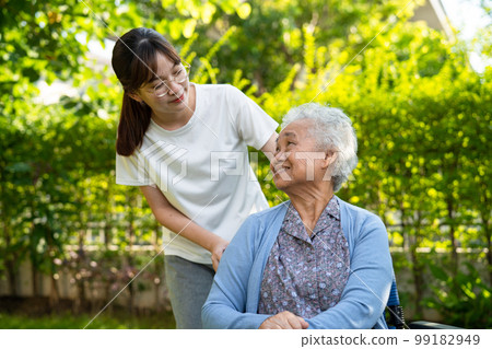 Caregiver help and care Asian elderly woman use walker with strong health while walking at park in happy fresh holiday. 99182949