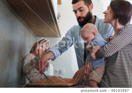 Family of 4 posing in the kitchen smiling and happy Family of 4 posing in the kitchen smiling and happy 99183897