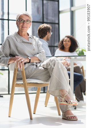 mature woman sitting with laptop looking at camera mature woman sitting with laptop looking at camera 99183907