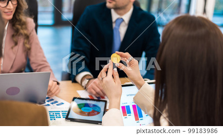 Female worker holding a physical cryptocurrency coin in an office Female worker holding a physical cryptocurrency coin in an office 99183986