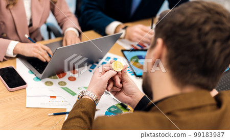 Worker holding a physical cryptocurrency coin in an office Worker holding a physical cryptocurrency coin in an office 99183987