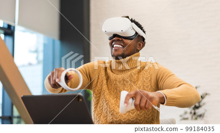 An excited black man exploring virtual reality in an office An excited black man exploring virtual reality in an office 99184035