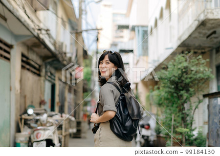 Young Asian woman backpack traveler enjoying street cultural local place and smile. Traveler checking out side streets. Young Asian woman backpack traveler enjoying street cultural local place and smile. Traveler checking out side streets. 99184130