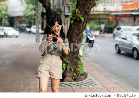 Young Asian woman backpack traveler using digital compact camera, enjoying street cultural local place and smile. Young Asian woman backpack traveler using digital compact camera, enjoying street cultural local place and smile. 99184139