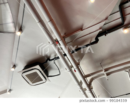 Ceiling mounted cassette type air conditioner and modern lamp light on white ceiling. duct air conditioner for home or office Ceiling mounted cassette type air conditioner and modern lamp light on white ceiling. duct air conditioner for home or office 99184339
