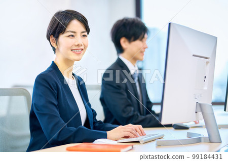 Smiling middle-aged business woman operating a computer in the office Smiling middle-aged business woman operating a computer in the office 99184431