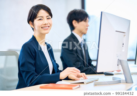 Smiling middle-aged business woman operating a computer in the office Smiling middle-aged business woman operating a computer in the office 99184432