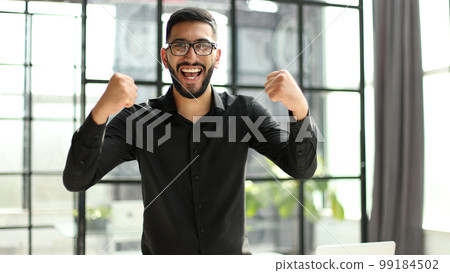 young businessman celebrating success in his home office 99184502