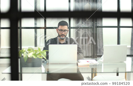 Businessman with glasses in the office working on a laptop 99184520