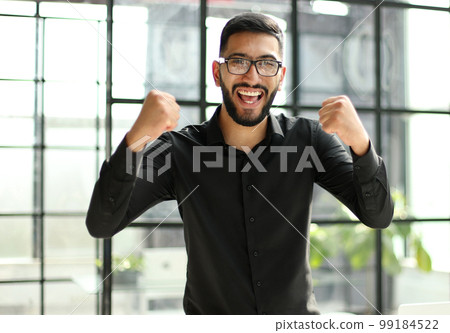 young businessman celebrating success in his home office 99184522