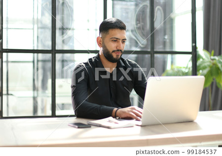 Focused young man wearing using laptop on keyboard, writing email or message 99184537