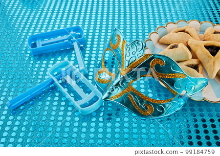 Purim celebration concept. Jewish carnival background. hamantaschen or hamans ears cookies, carnival mask and noisemaker 99184759
