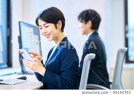 一位穿著西裝的中層女商人在辦公室的辦公桌前工作時操作智能手機 99184763