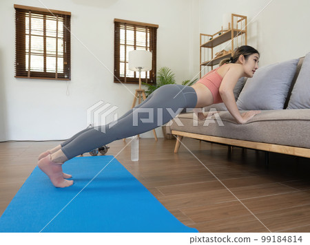Young woman doing workout at home happily Young woman doing workout at home happily 99184814