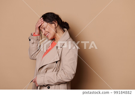 Middle-aged pretty woman in casual coat, laughing and smiling over a beige color background. Successful people concept Middle-aged pretty woman in casual coat, laughing and smiling over a beige color background. Successful people concept 99184882