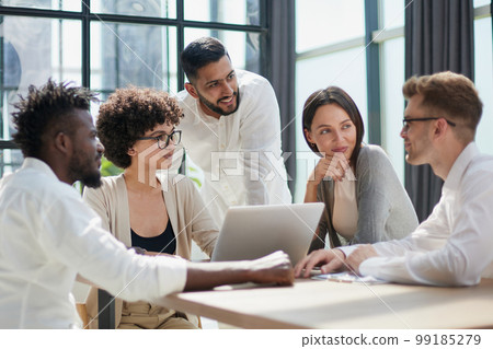 Employees working at computer together, discussing content 99185279