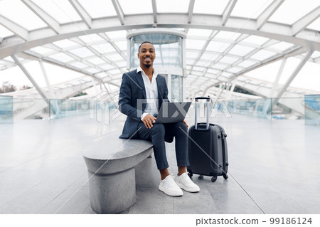 Digital Nomad. Young Black Man Using Laptop In Airport While Waiting Flight Digital Nomad. Young Black Man Using Laptop In Airport While Waiting Flight 99186124