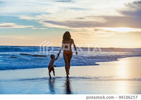 Happy mother, baby son run with fun by sand beach 99186257